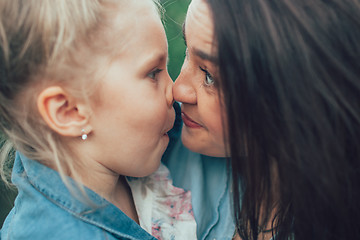 Image showing The young mother and daughter on green grass background 