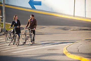 Image showing Young couple with a bicycle opposite city 