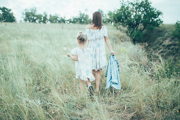 Image showing The young mother and daughter on green grass background 