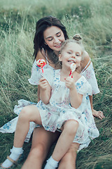 Image showing The young mother and daughter on green grass background 