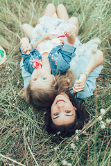 Image showing The young mother and daughter on green grass background 