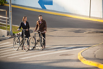 Image showing Young couple with a bicycle opposite city 