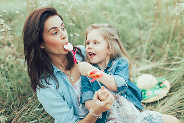 Image showing The young mother and daughter on green grass background 