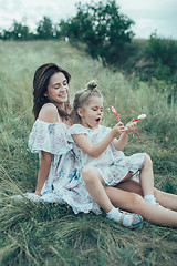 Image showing The young mother and daughter on green grass background 