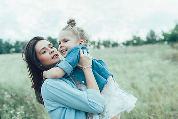 Image showing The young mother and daughter on green grass background 