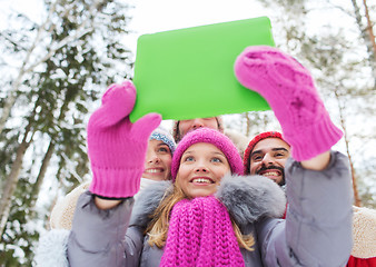 Image showing smiling friends with tablet pc in winter forest