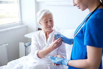 Image showing nurse giving medicine to senior woman at hospital