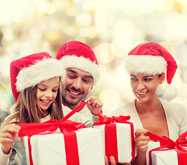 Image showing happy family in santa hats sitting with gift boxes