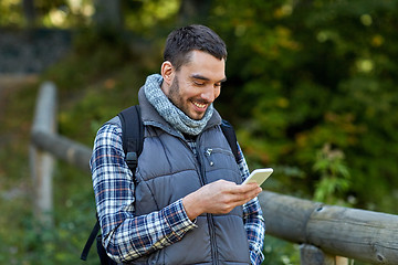 Image showing happy man with backpack and smartphone outdoors