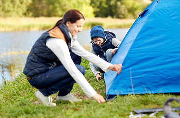 Image showing happy mother and son setting up tent outdoors