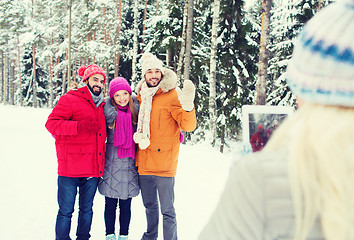 Image showing smiling friends with tablet pc in winter forest