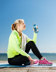 Image showing woman drinking water after doing sports outdoors