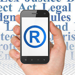 Image showing Law concept: Hand Holding Smartphone with Registered on display