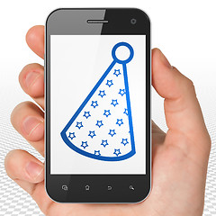 Image showing Holiday concept: Hand Holding Smartphone with Party Hat on display