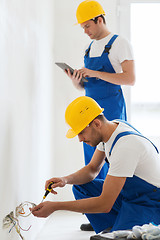 Image showing builders with tablet pc and fixing wiring indoors