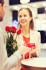 Image showing happy couple with present and flowers in mall