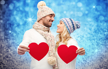 Image showing smiling couple in winter clothes with red hearts