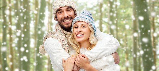 Image showing happy couple in winter clothes hugging over forest