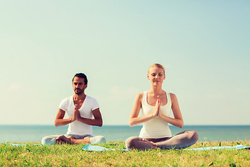 Image showing smiling couple making yoga exercises outdoors