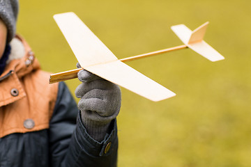 Image showing close up of little boy holding toy plane outdoors