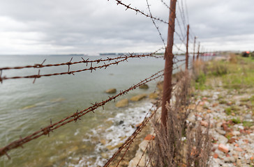 Image showing barb wire fence over gray sky and sea