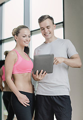 Image showing smiling young woman with personal trainer in gym