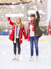 Image showing happy girls friends waving hands on skating rink