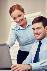 Image showing smiling businesspeople with laptop in office