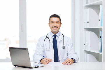 Image showing smiling male doctor with laptop in medical office