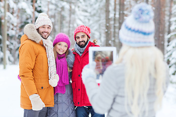 Image showing smiling friends with tablet pc in winter forest