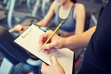 Image showing close up of trainer hands with clipboard in gym