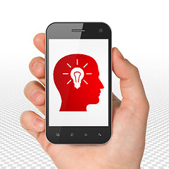 Image showing Business concept: Hand Holding Smartphone with Head With Light Bulb on display