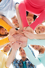 Image showing smiling teenagers with hands on top of each other