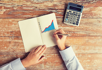 Image showing close up of hands with calculator and notebook