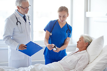 Image showing doctor giving medicine to senior woman at hospital