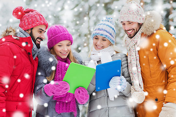 Image showing smiling friends with tablet pc in winter forest