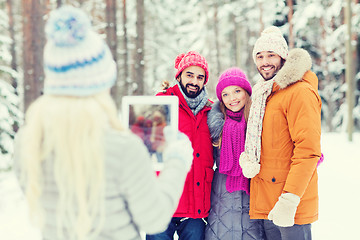 Image showing smiling friends with tablet pc in winter forest