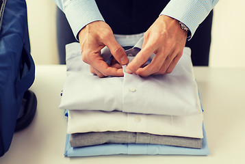 Image showing businessman packing clothes into travel bag