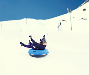 Image showing happy young man sliding down on snow tube