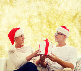 Image showing happy senior couple in santa hats with gift box