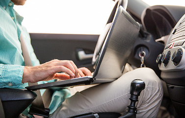 Image showing close up of young man with laptop driving car