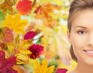 Image showing beautiful young woman face over autumn leaves