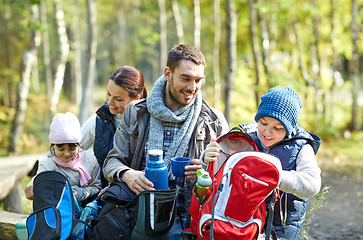 Image showing happy family with backpacks and thermos at camp