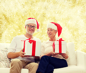 Image showing happy senior couple in santa hats with gift boxes