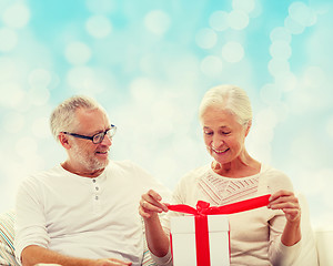 Image showing happy senior couple with gift box at home