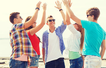 Image showing group of smiling friends making high five outdoors