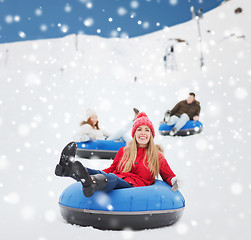 Image showing group of happy friends sliding down on snow tubes