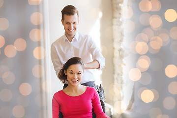 Image showing happy woman with stylist making hairdo at salon