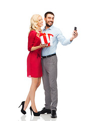 Image showing happy couple with smartphone and gift boxes