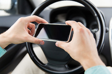 Image showing close up of man hand with smartphone driving car